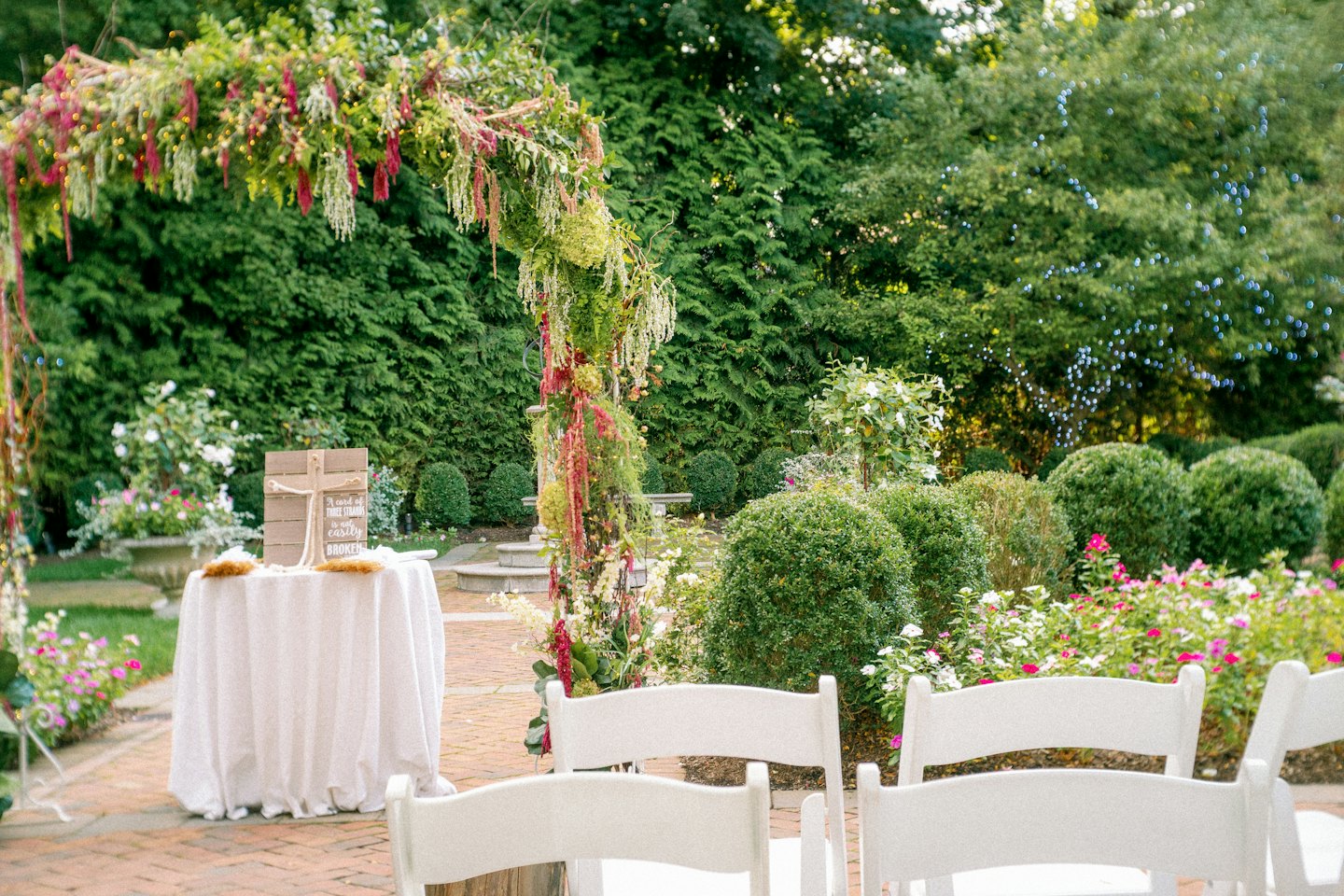 Floral arch standing over a garden wedding ceremony seating area.