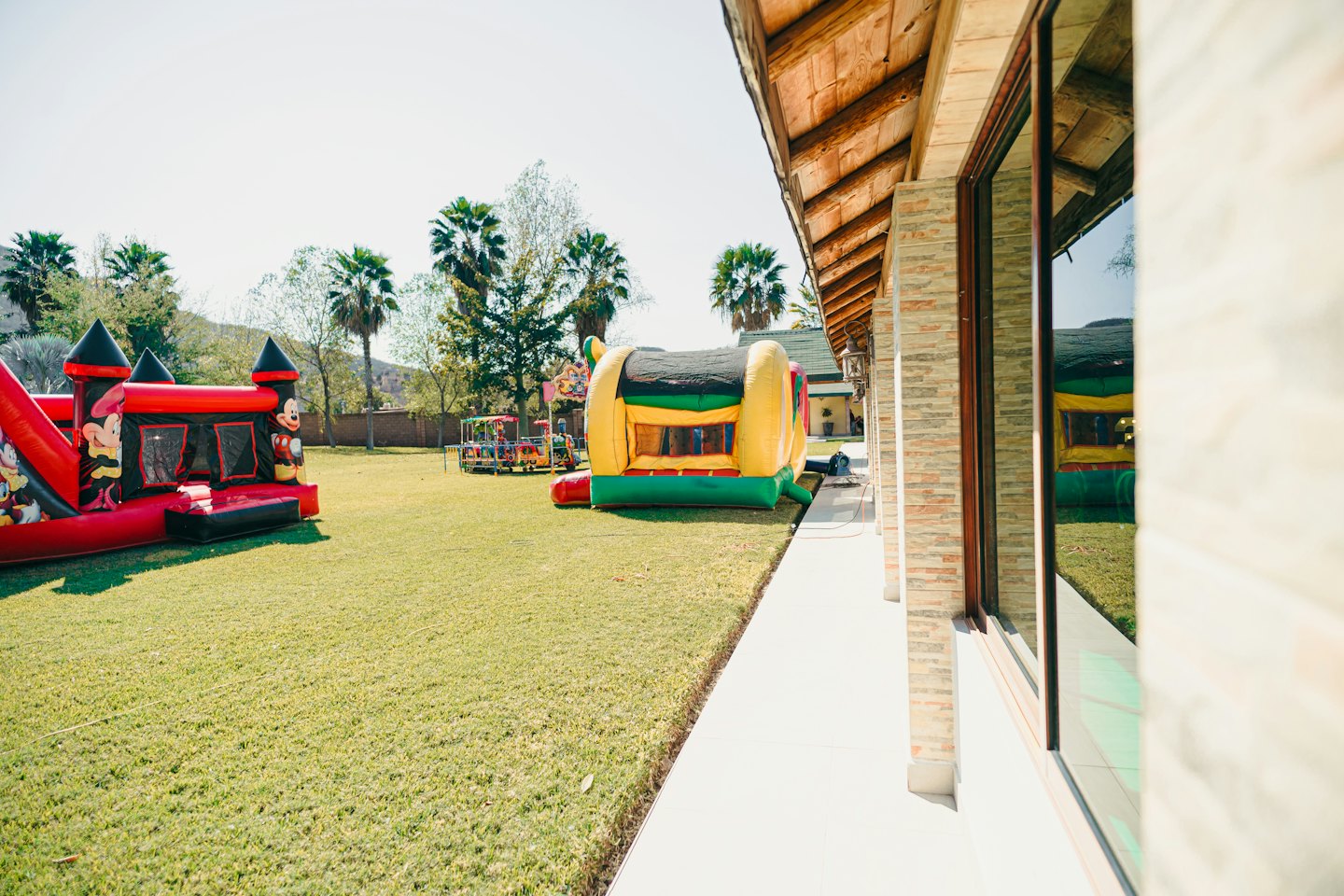 Inflatable bouncy castles and an amusement ride on a lawn.