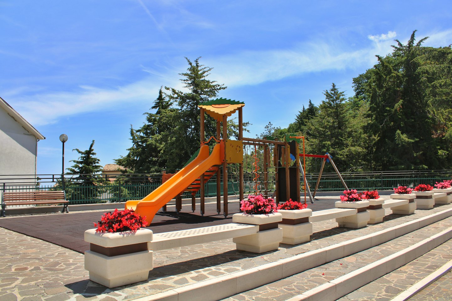 Children play on a climbing frame and slide in a park.